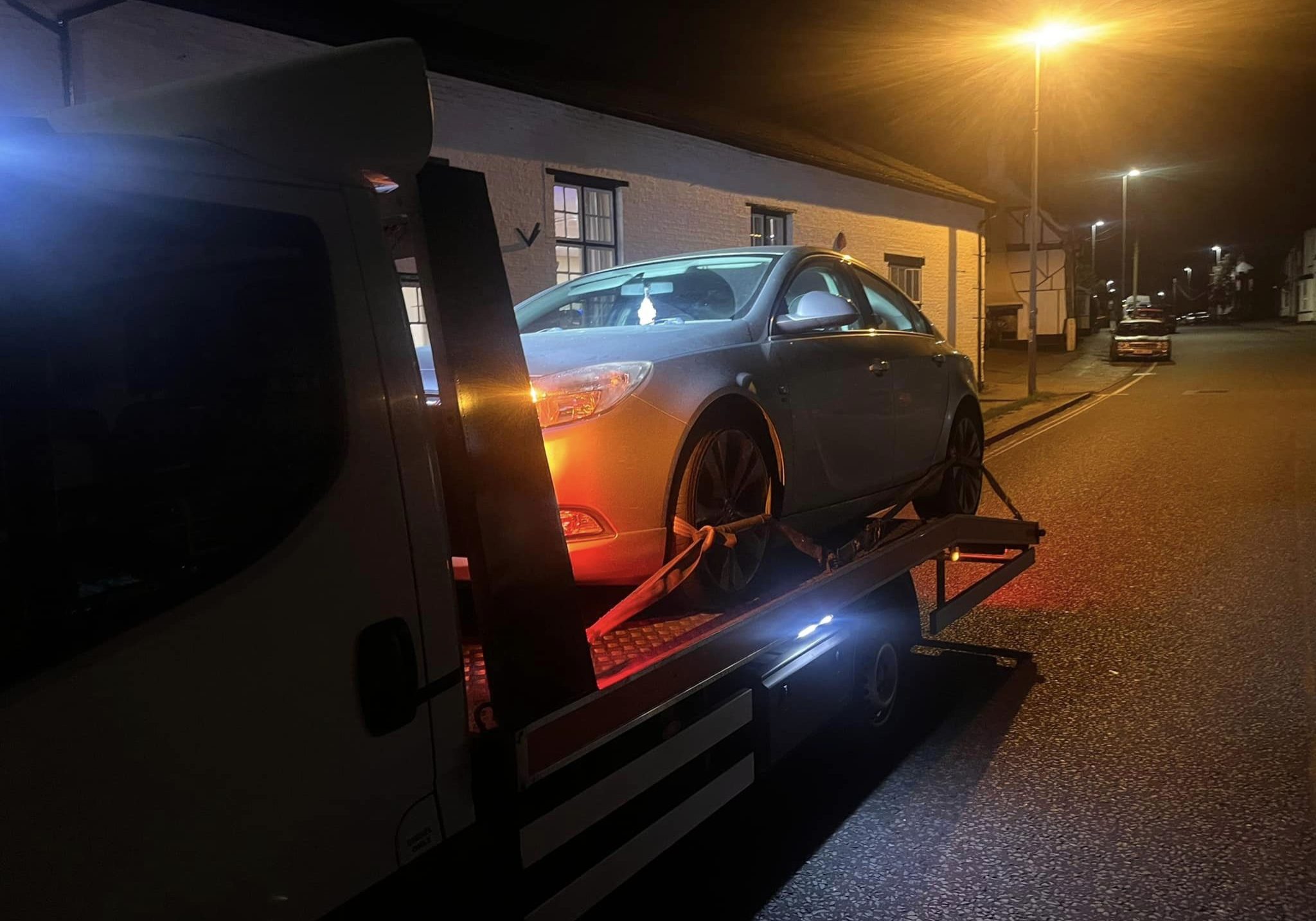 car on recovery truck at night